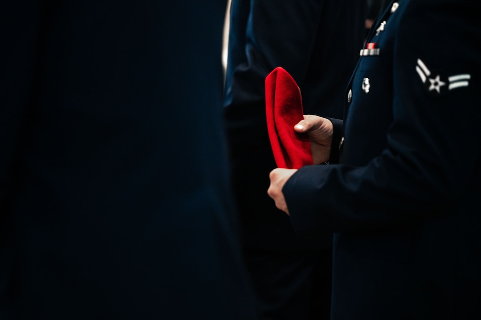 Airman in blue dress uniform holds his red beret