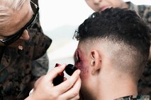 U.S. Sailors with Bravo Surgical Company, 3rd Medical Battalion, 3rd Marine Logistics Group, apply trauma makeup to simulate injuries during a field exercise at Marine Corps Training Area Bellows, Hawaii, May 17, 2023. The purpose of the exercise was to test lower level medical capabilities and increase medical readiness by providing care in the air and on the ground during evacuations to higher echelons of care. (U.S. Marine Corps photo by Cpl. Christian Tofteroo)