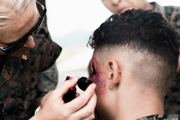U.S. Sailors with Bravo Surgical Company, 3rd Medical Battalion, 3rd Marine Logistics Group, apply trauma makeup to simulate injuries during a field exercise at Marine Corps Training Area Bellows, Hawaii, May 17, 2023. The purpose of the exercise was to test lower level medical capabilities and increase medical readiness by providing care in the air and on the ground during evacuations to higher echelons of care. (U.S. Marine Corps photo by Cpl. Christian Tofteroo)