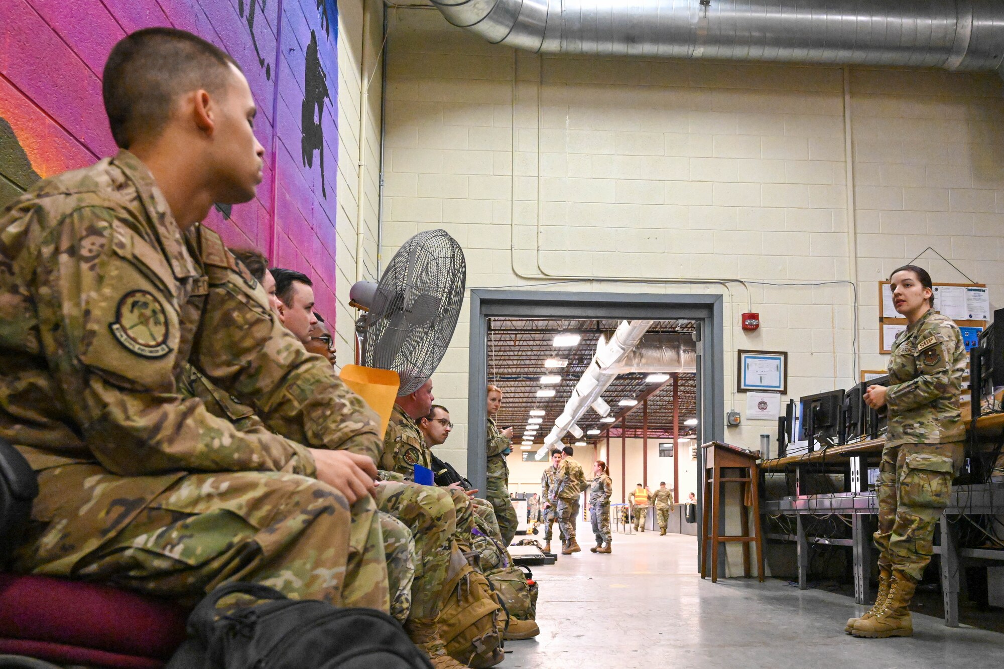 U.S. Air Force Tech. Sgt. Cassandra Vandermay, 97th Logistics Readiness Squadron individual protective equipment non-commissioned officer in charge, briefs Airmen about their deployment bags during an exercise at Altus Air Force Base, Oklahoma, May 2, 2023. During the exercise, each Airmen was provided a mock deployment bag that included Mission Oriented Protective Posture gear. (U.S. Air Force photo by Senior Airman Trenton Jancze)