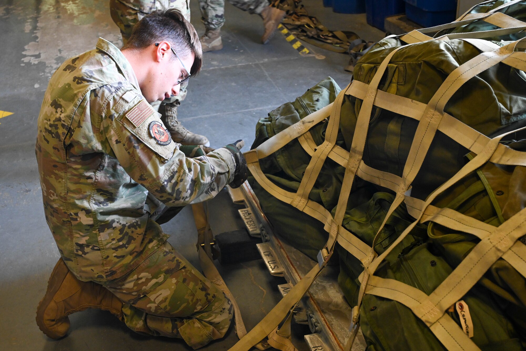 U.S. Air Force Airman 1st Class Gabriel Fry, 97th Logistics Readiness Squadron unilateral aircrew training element member, straps down a pallet during an exercise at Altus Air Force Base, Oklahoma, May 2, 2023. The Airmen from the 97th Air Mobility Wing that participated in the exercise went through a full mock deployment line that included receiving a deployment bag, meeting with several agencies and hearing pre-deployment briefs. (U.S. Air Force photo by Senior Airman Trenton Jancze)