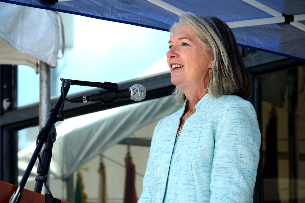 Nancy Norton speaking in front of a podium microphone