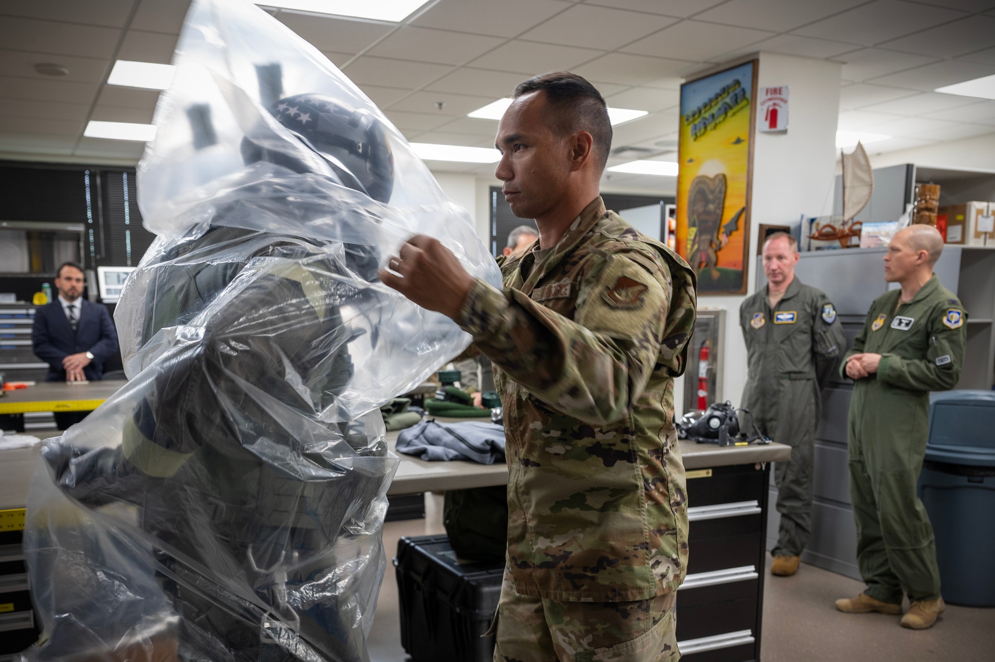 U.S. Air Force Master Sgt. Terrance Akana, 154th Operations Support Squadron aircrew flight equipment craftsman, utilizes an over-cloak that provides an extra layer of protection on Capt. Alex “Doom” Moss, 19th Fighter Squadron F-22 Raptor pilot, during a Next Generation Aircrew Protection Step-Launch and Recover concept of operation demonstration, Joint-Base Pearl Harbor-Hickam, Hawaii, May 11, 2023. The demonstration showcases the Pacific Air Forces stop gap for the F-22 Aircrew Chemical, Biological, Radiological and Nuclear limiting factor utilizing the modified M-50 ground crew mask. (U.S. Air National Guard photo by Master Sgt. Mysti Bicoy)