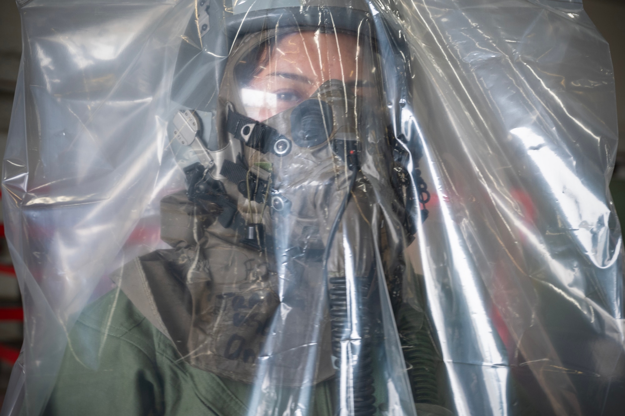 U.S. Air Force Airman Kyla Correos, 15th Operations Support Squadron aircrew flight equipment specialist, utilizes
an over-cloak that provides an extra layer of protection during a Next Generation Aircrew Protection Step-Launch and Recover concept of operation demonstration, Joint-Base Pearl Harbor-Hickam, Hawaii, May 11, 2023. The demonstration showcases the Pacific Air Forces stop gap for the F-22 Aircrew Chemical, Biological, Radiological and Nuclear limiting factor utilizing the modified M-50 ground crew mask. (U.S. Air National Guard photo by Master Sgt. Mysti Bicoy)