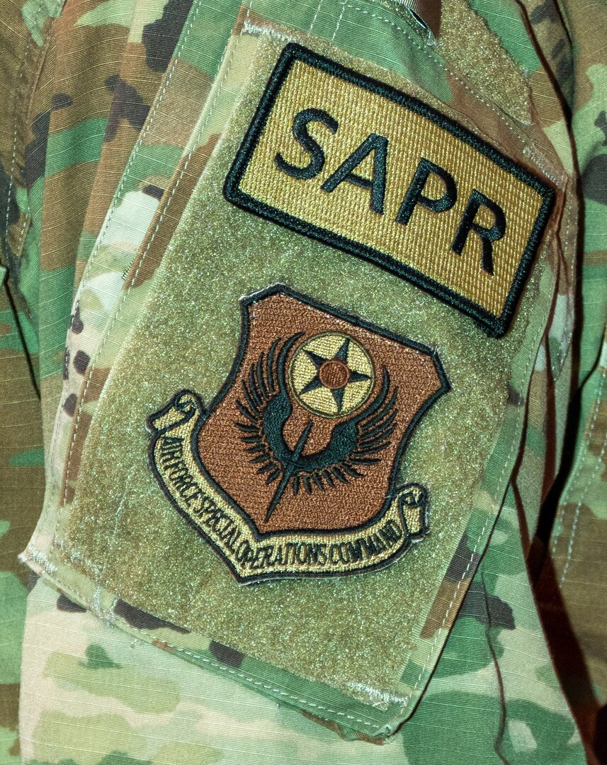 A patch with the letters SAPR is displayed on a uniform.