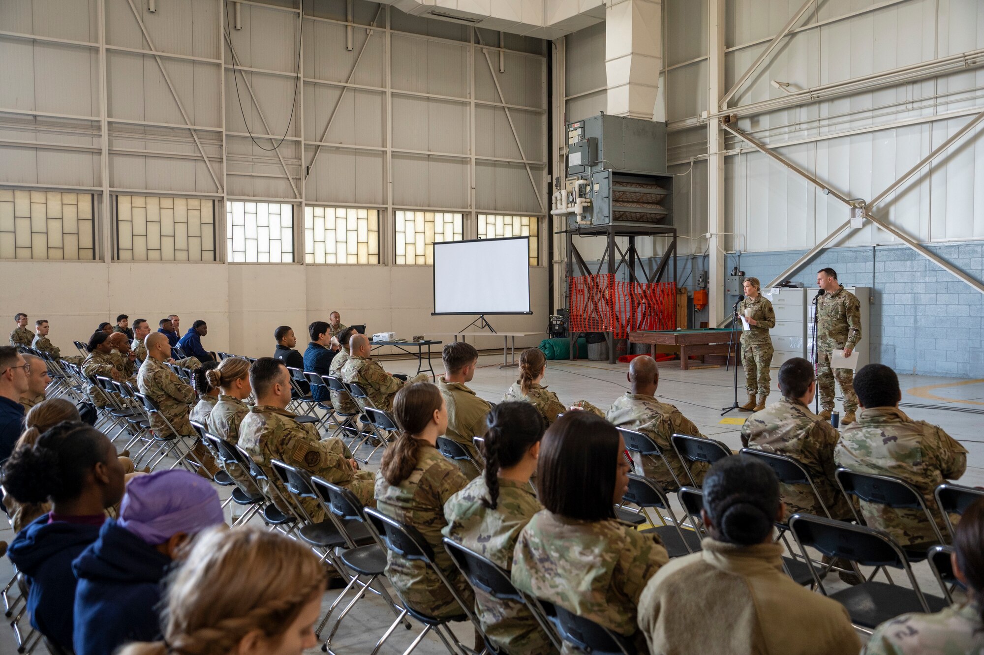 An audience in military uniform listens to a brief.