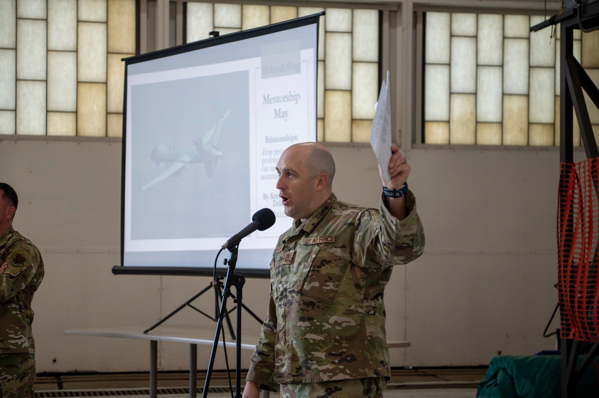 An audience in military uniform listens to a brief.