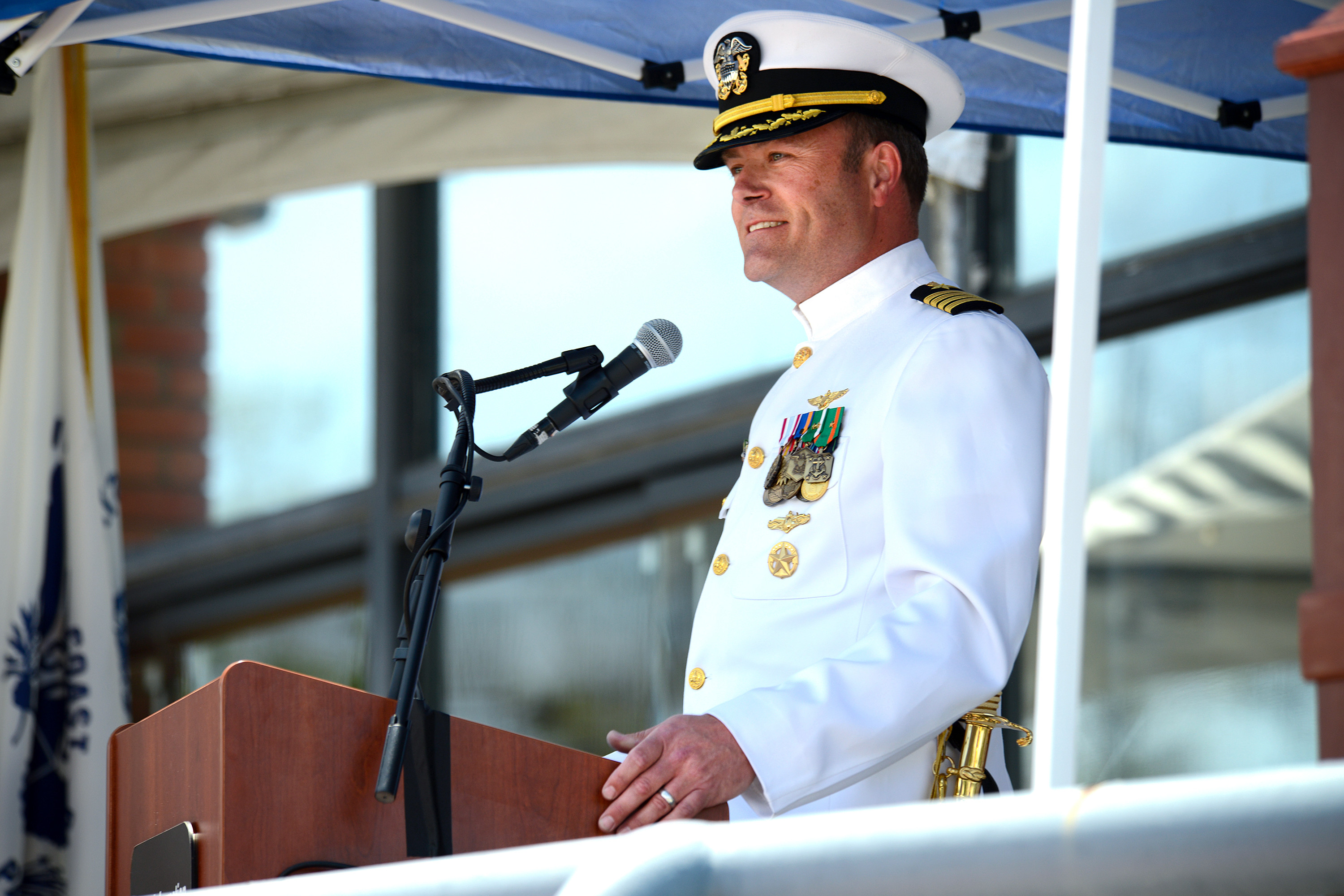 Captain McKenna speaking at a podium microphone