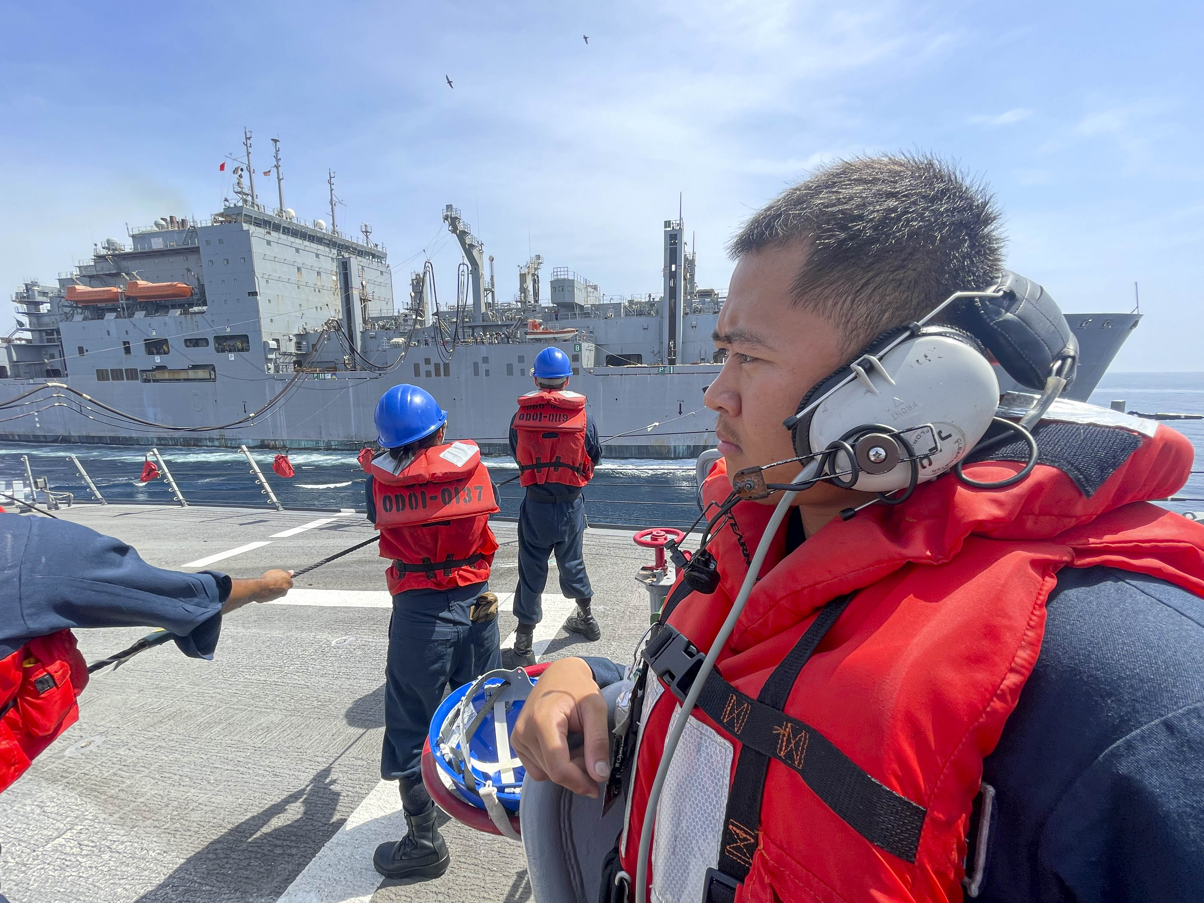 Logistics Specialist Seaman Ranilo Dulatre mans a forward phone talker station on the foc'scle of the guided-missile destroyer USS Paul Hamilton (DDG 60) during a replenishment-at-sea with the dry cargo and ammunition ship USNS Amelia Earhart.