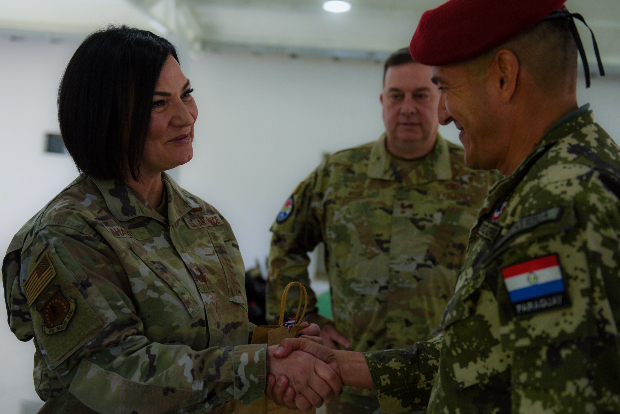 U.S. Air Force Col. Lisa Ahaesy, the director of staff of the Massachusetts Air National Guard, shakes hands with a member of the Paraguayan army at a State Partnership Program event in Asunción, Paraguay, May 18, 2023. Ahaesy supported the delivery of more than 1,000 sets of personal protective firefighting equipment donated by Massachusetts fire departments, facilitated by the Massachusetts National Guard and the Military Division of the Commonwealth of Massachusetts.