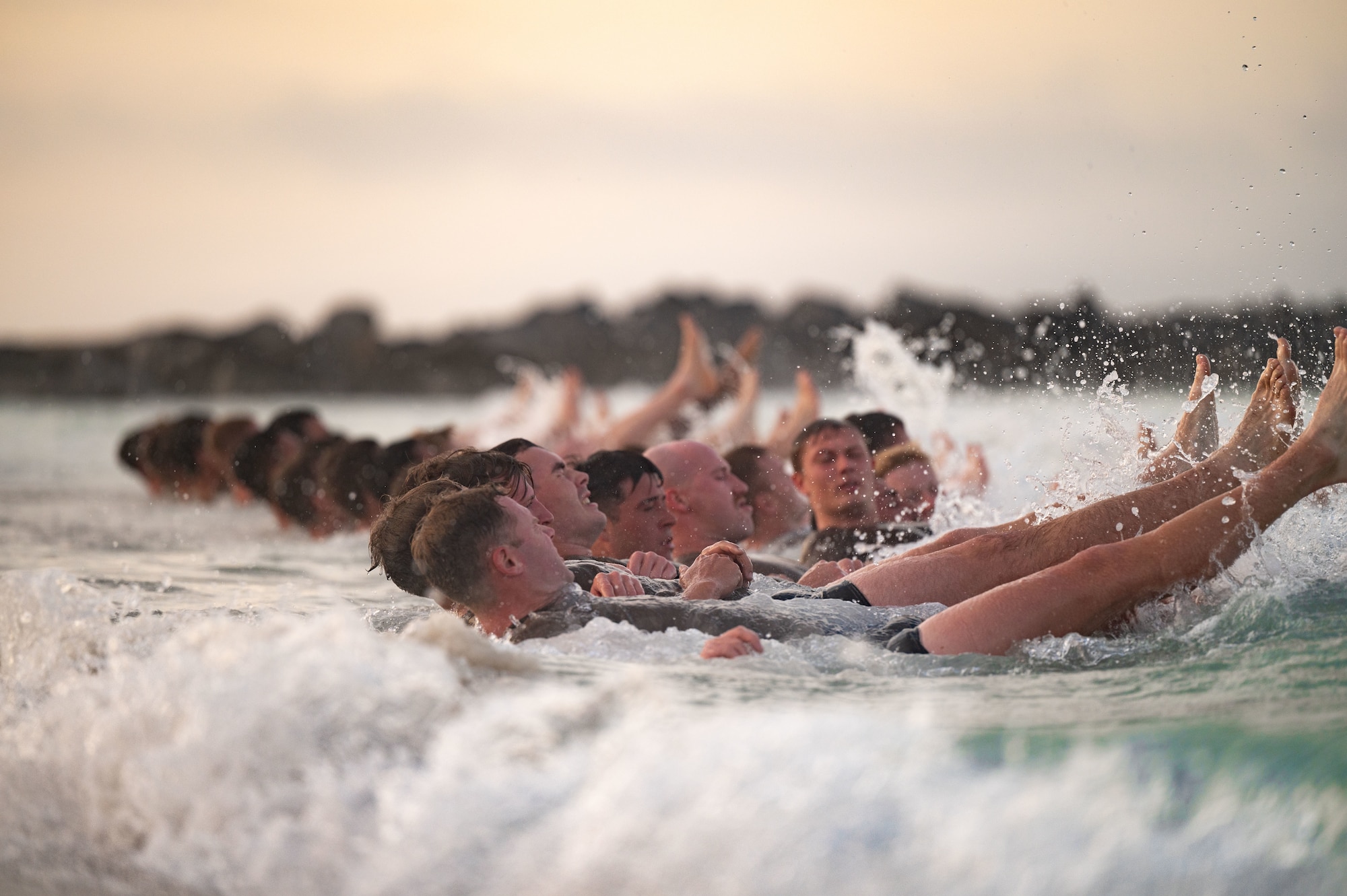 students flutter kick in the ocean while the waves hit the shore