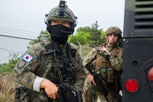 8th Security Forces Squadron police service non-commissioned officer in charge, communicates with other team leaders over the radio while taking cover behind a Humvee during a training event with Republic of Korea Army soldiers at Kunsan Air Base