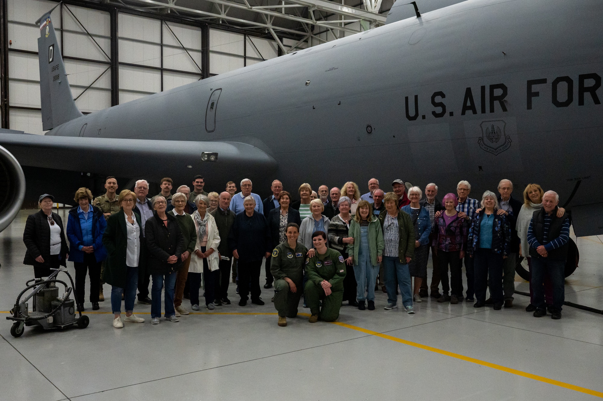 U.S. Air Force Airmen and members of the University of the Third Age stand together for a group photo in front of a KC-135 Stratotanker aircraft during a base tour at Royal Air Force Mildenhall, England, May 16, 2023.