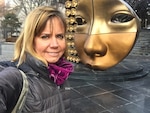 A woman poses in front of an art installation.