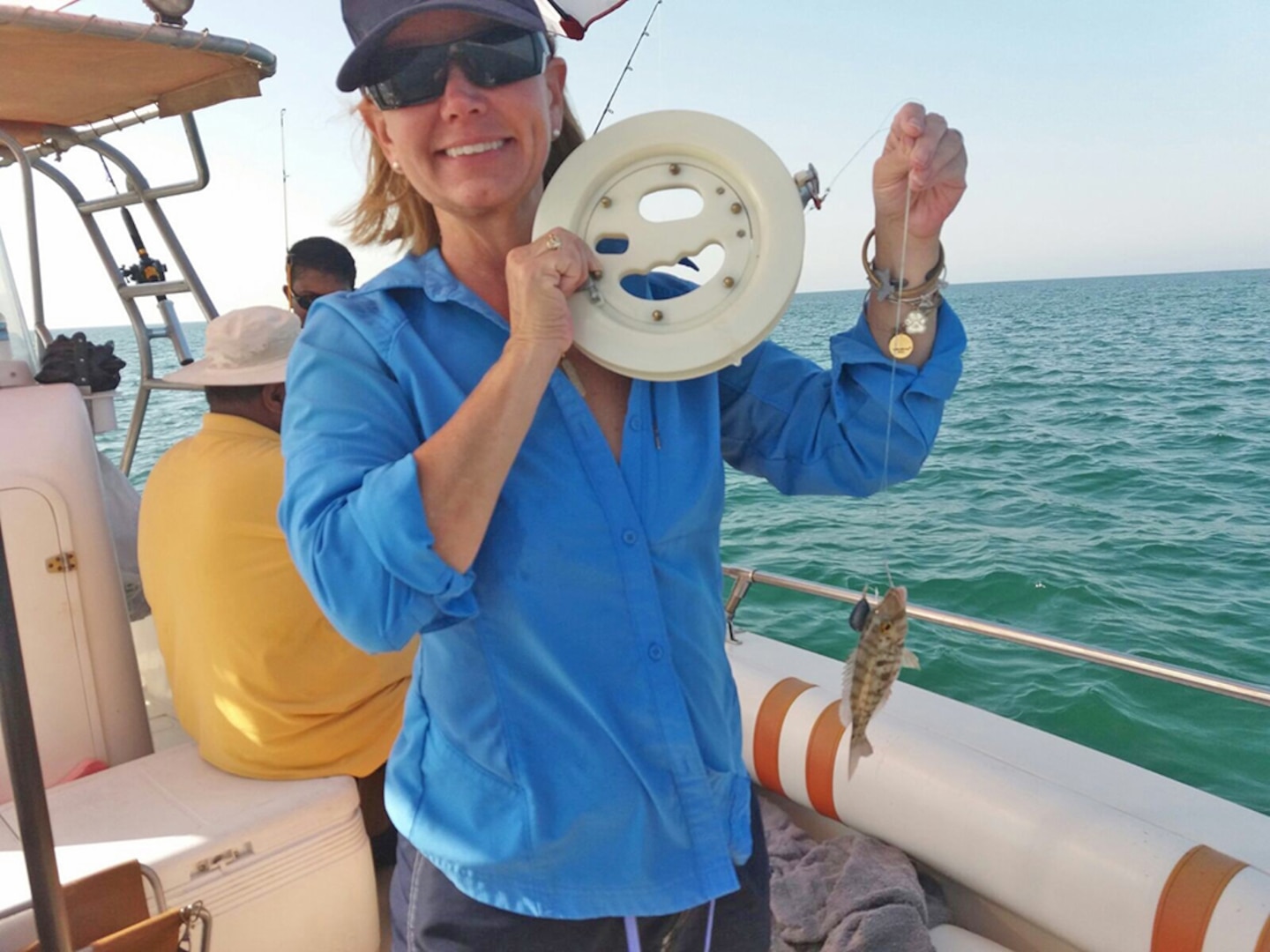 A woman on a boat holds up a fish