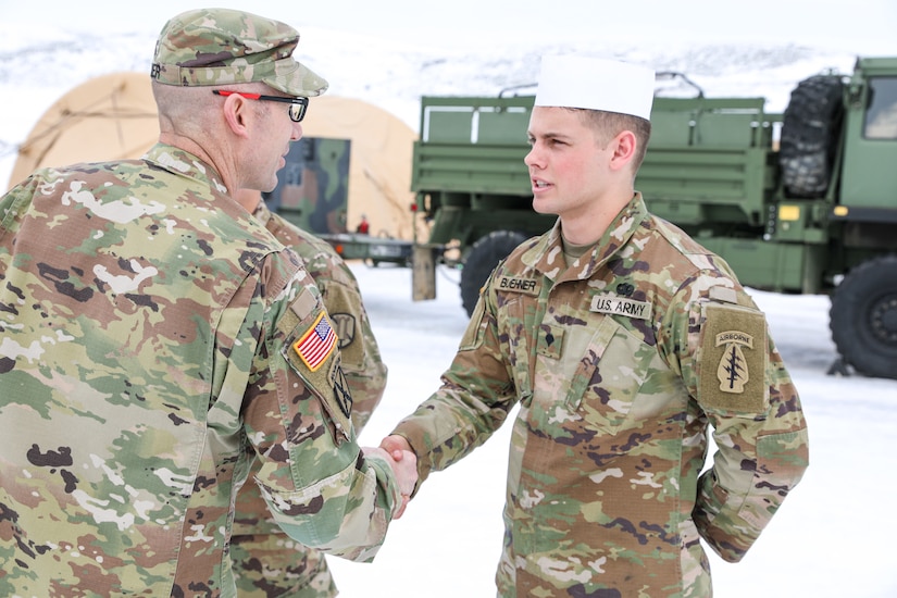 Spc Bridger Buehner, a food service specialist assigned to the 19th Special Forces Group Support Battalion, receives a coin from Col. Woodrow Miner, commander of the 204th Maneuver Enhancement Brigade, during the “Final Four” of the Philip A. Connelly Competition at Camp Williams, Utah, February 25, 2023. The Philip A. Connelly Award is given to the best food services organization in the Army. (US Army photo by Sgt. 1st Class Rich Stowell)