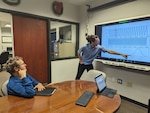 (center) Ben Colburn, a research assistant at the University of Florida, presents his research to Dr. Matthew Bays, Naval Surface Warfare Center Panama City Division's (NSWC PCD) senior scientist for robotics and optimization and the command's Naval Engineering Education Consortium (NEEC) director. The NEEC program has benefited the Naval Research and Development Enterprise and Navy Labs, like NSWC PCD, by creating a sustainable pipeline of scientists and engineers with difficult-to-hire skillsets. (courtesy photo)