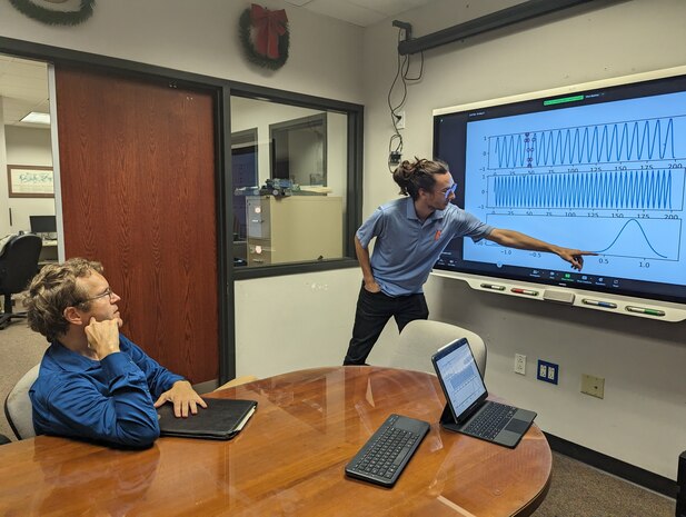 (center) Ben Colburn, a research assistant at the University of Florida, presents his research to Dr. Matthew Bays, Naval Surface Warfare Center Panama City Division's (NSWC PCD) senior scientist for robotics and optimization and the command's Naval Engineering Education Consortium (NEEC) director. The NEEC program has benefited the Naval Research and Development Enterprise and Navy Labs, like NSWC PCD, by creating a sustainable pipeline of scientists and engineers with difficult-to-hire skillsets. (courtesy photo)