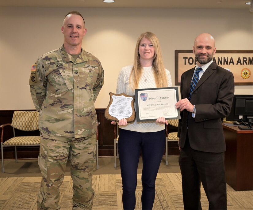 Photo of employee posing with awards given by Depot Commander and Deputy Commander