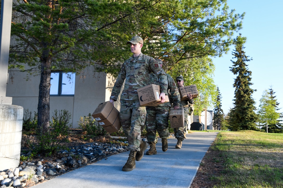 From the front, Senior Airman Jakob Stokes, Senior Airman Sean Lake, and Tech Sgt. Vincent McKiernan, 168th Wing, Alaska Air National Guard, carry meals, ready to eat to a government vehicle in preparation to travel to Circle, Alaska, May 23, 2023, to support flood-recovery operations. Four Guardsmen and one member of the Alaska State Defense Force will assist with cleanup and flood recovery efforts at the request of the Alaska State Emergency Operations Center. (Alaska Air National Guard photo by Senior Master Sgt. Julie Avey)