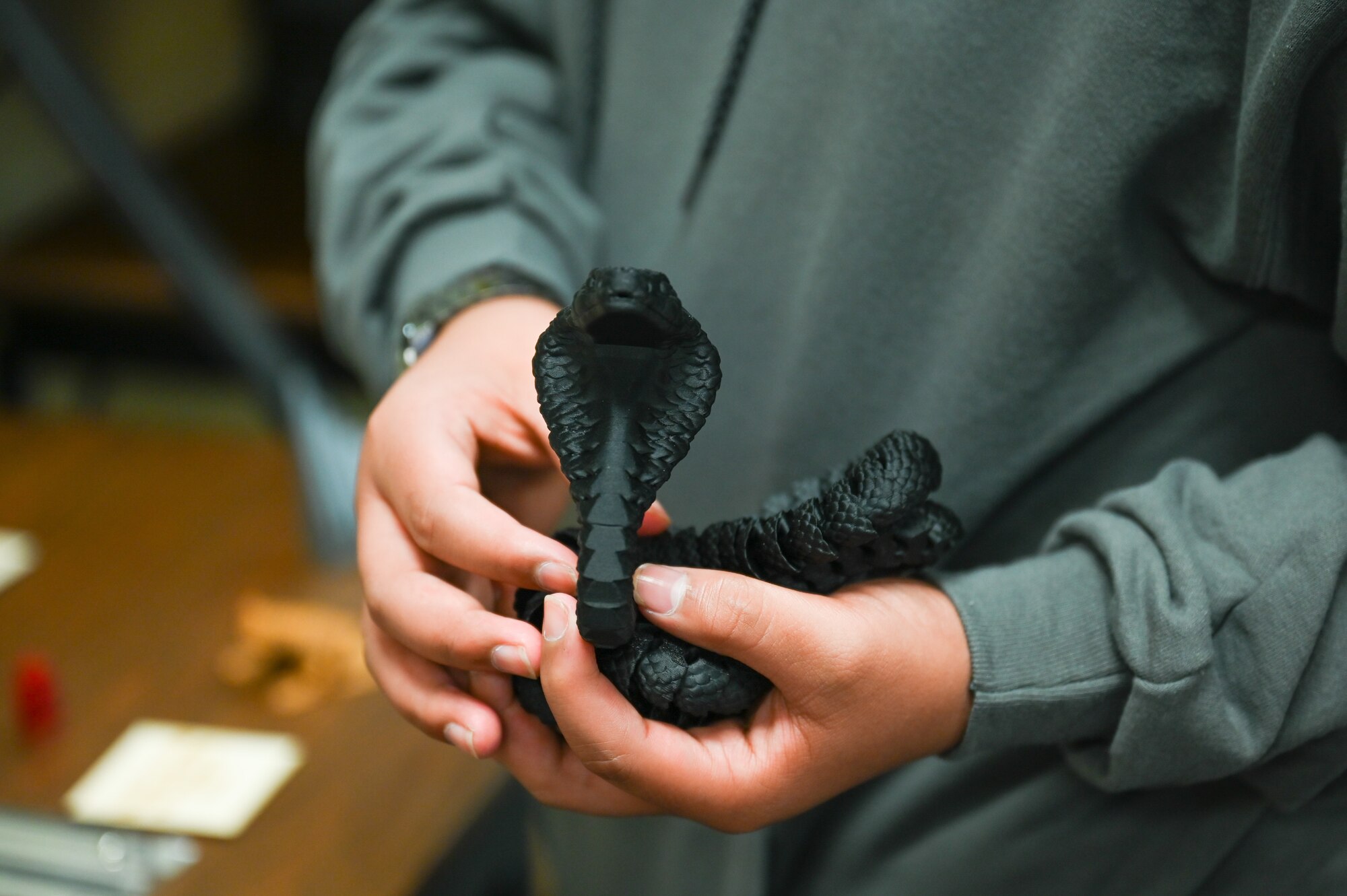 A student from Navajo Public Schools holds a snake figurine created by a 3-D printer during the Aviation Inspiration and Mentorship Wing tour at Altus Air Force Base, Oklahoma, May 10, 2023. The students were able to watch 3-D printers in action while touring the Spark Cell innovation hub. (U.S. Air Force photo by Airman 1st Class Heidi Bucins)