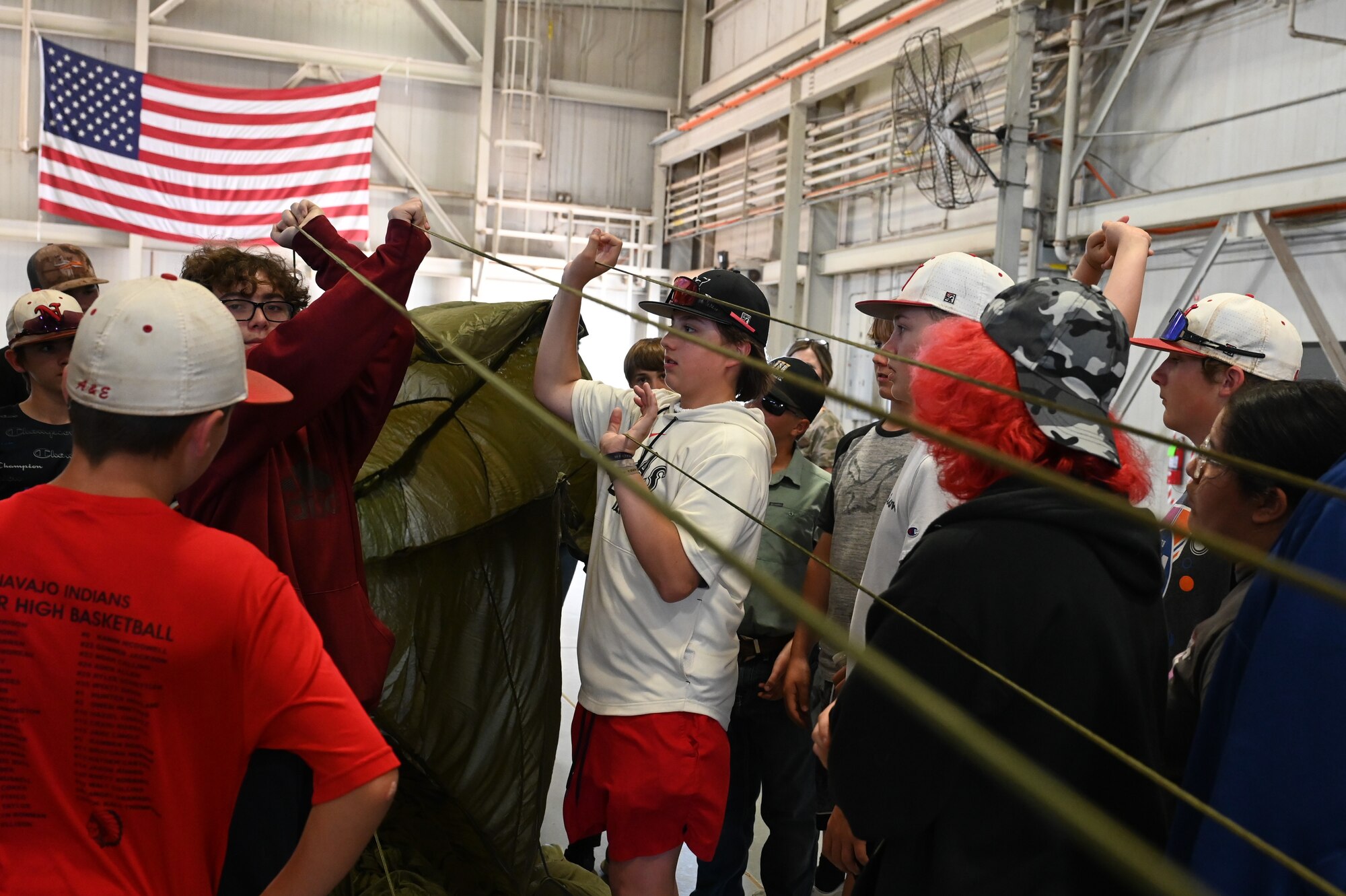 Students from Navajo Public Schools inflate a parachute at the 97th Logistics Readiness Squadron during the Aviation Inspiration and Mentorship Wing tour at Altus Air Force Base, Oklahoma, May 10, 2023. The students utilized team building skills to complete the activity. (U.S. Air Force photo by Airman 1st Class Heidi Bucins)
