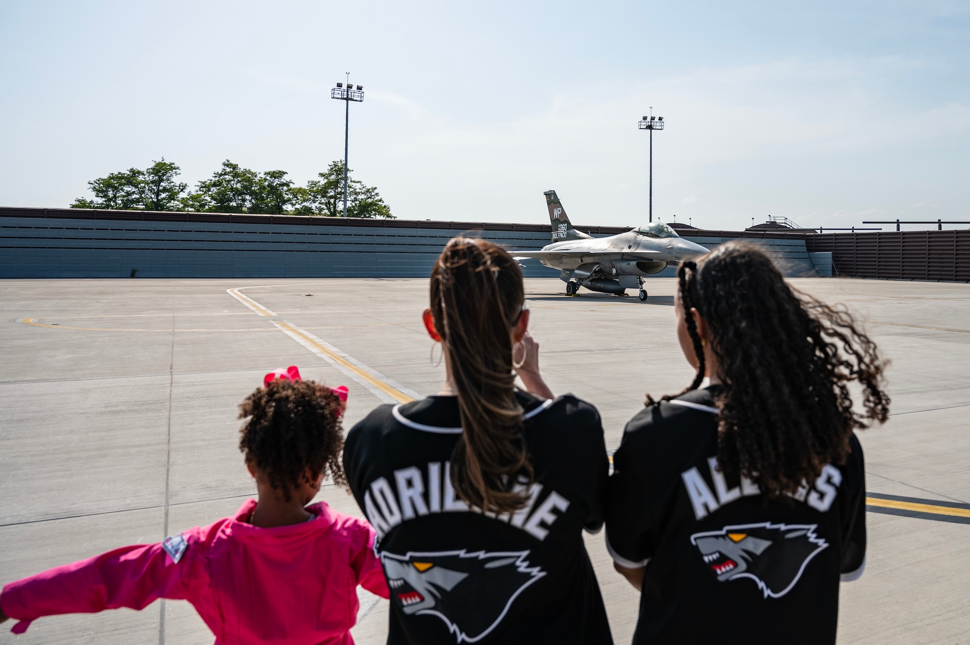 Adrienne Jeffress, center, spouse of Col. Henry R. Jeffress, III, 8th Fighter Wing commander, and their daughters, Amelia Jeffress, right, and Alexis Jeffress, left, prepare to receive their father as he taxis in an F-16 Fighting Falcon at Osan Air Base, Republic of Korea, May 17, 2023. The final flight marks a milestone in Jeffress’ career signifying the end of his time at the Wolf Pack.  (U.S. Air Force photo by Capt. Kaylin P. Hankerson)