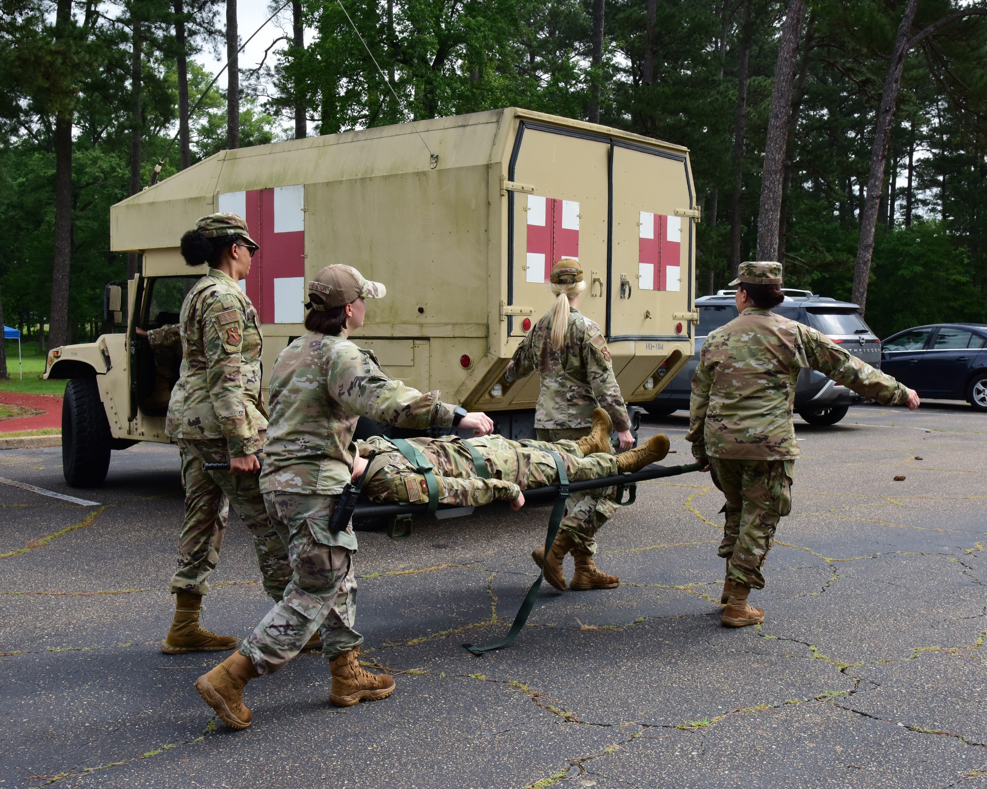 Military members carry a litter to a military medical Humvee.