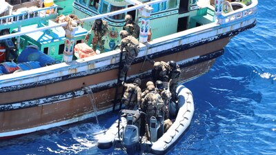 Personnel from a French warship board a fishing vessel during a drug seizure in the Indian Ocean.
