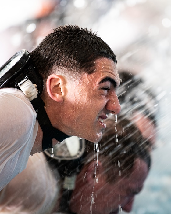 student sprayed with water as he prepares to enter pool