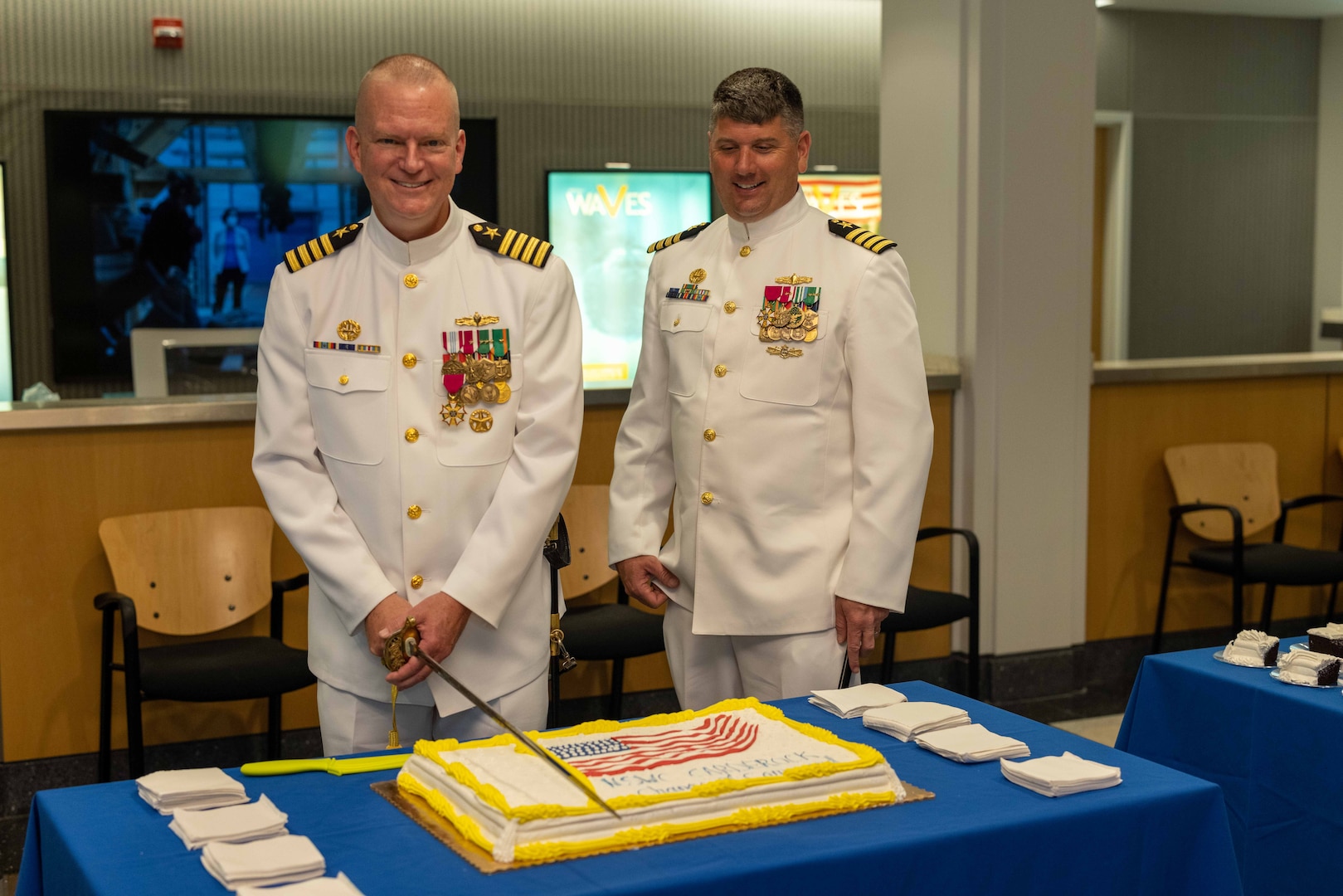 Naval Surface Warfare Center, Carderock Division’s outgoing Commanding Officer, Capt. Todd E. Hutchison (left), prepares to cut the cake while Carderock’s incoming Commanding Officer, Capt. Matthew Tardy, watches on during a change-of-command ceremony held in West Bethesda, Md., on May 12. (U.S. Navy photo by Aaron Thomas)