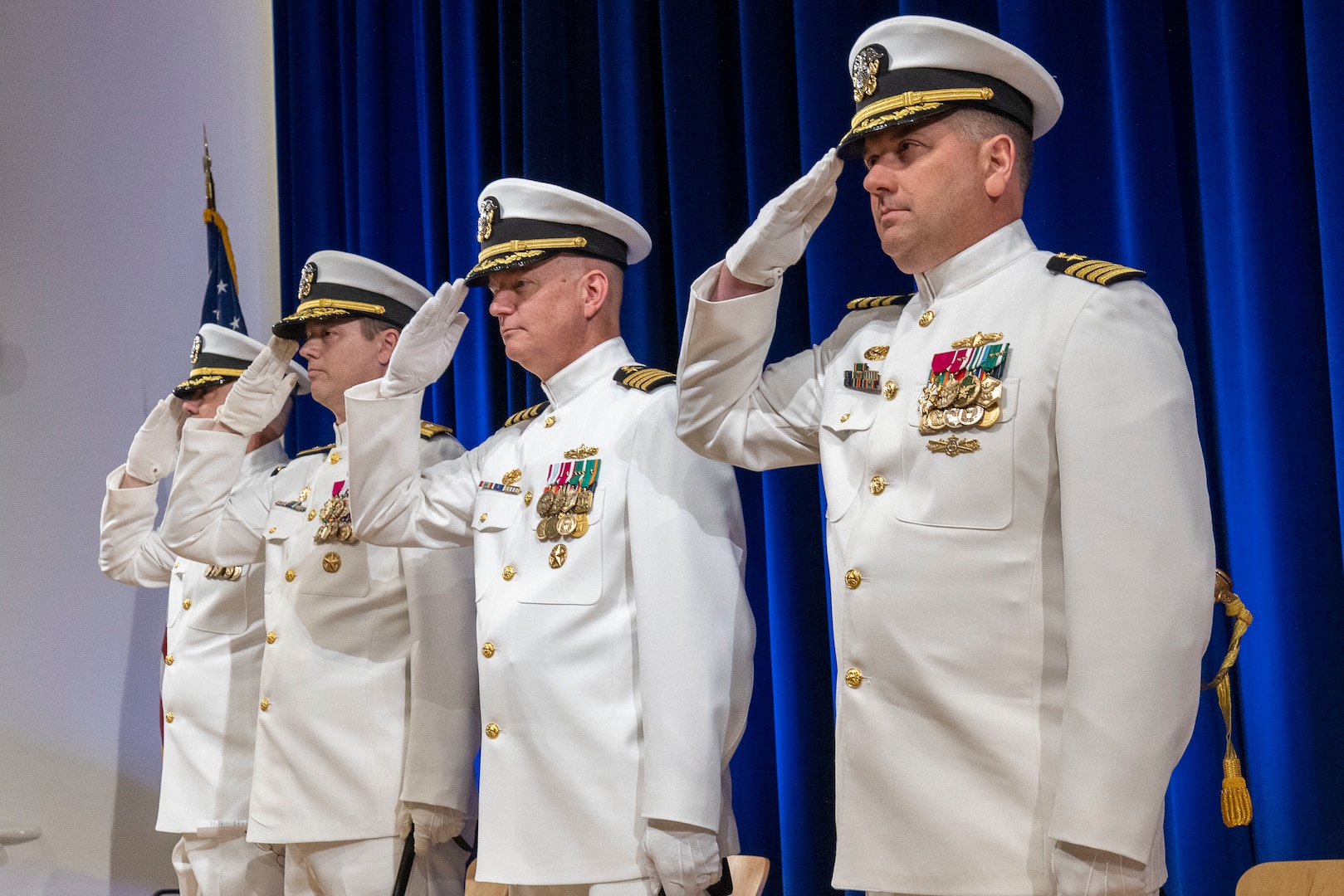 The official party, consisting of Capt. Aaron Stroud, Rear Adm. Kevin Byrne, Capt. Todd E. Hutchison and Capt. Matthew Tardy salute as the flag is presented during a change-of-command ceremony held in West Bethesda, Md., on May 12. (U.S. Navy photo by Devin Pisner)