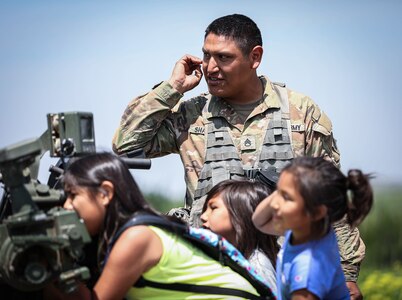 Staff Sgt. Lyndell Shawnee, a member of the 1st Battalion, 160th Field Artillery Regiment, 45th Infantry Brigade Combat Team shows his three daughters around an M119 howitzer after a family day live-fire demonstration on May 20, 2023 at Fort Sill, Oklahoma. The event was hosted by his unit in order to strengthen the bonds between the unit’s Soldiers and their families. (Oklahoma National Guard photo by Pfc. Anthony Ackah-Mensah)