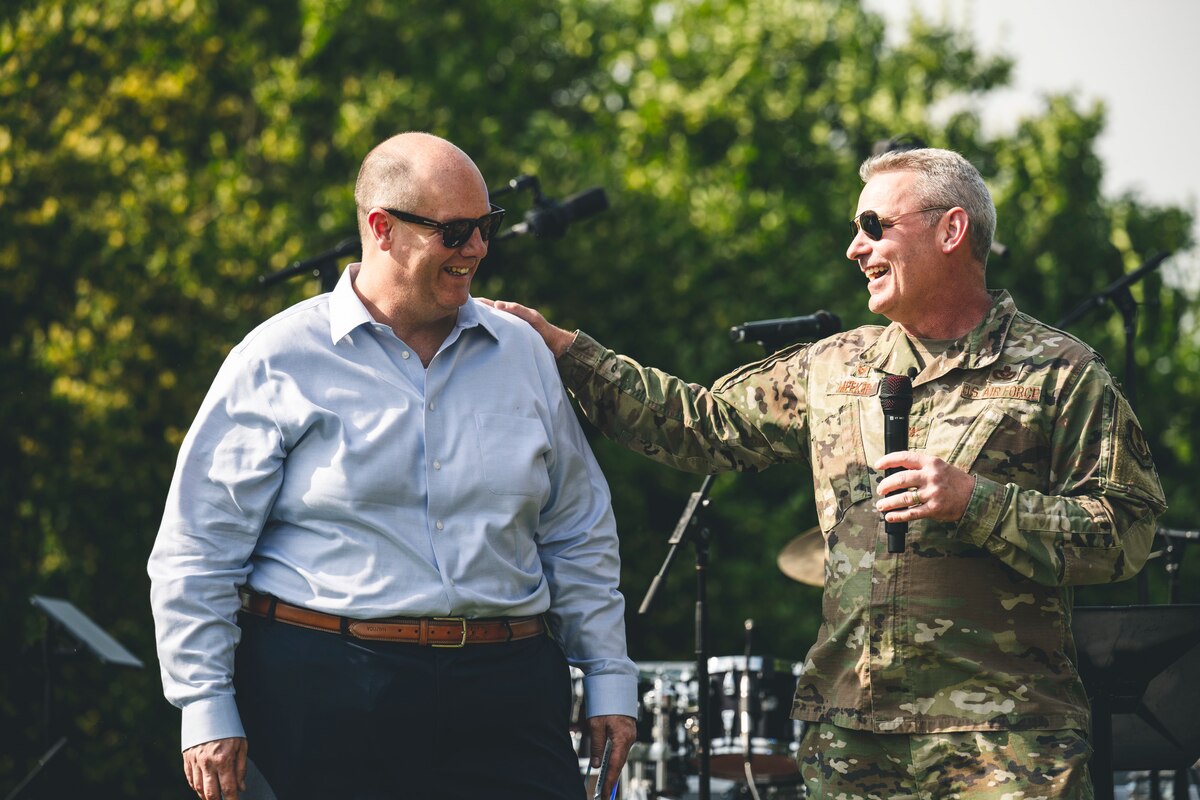 Two men speak on stage.