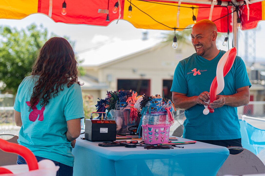 We Salute You event volunteers make balloon animals during the We Salute You Celebration on Victory Field, Marine Corps Air-Ground Combat Center, Twentynine Palms, California, May 6, 2023. Grammy-nominated rock band 3 Doors Down headlined this annual Marine Corps Community Services sponsored event meant to honor Combat Center service members and their families by providing food, activities and live entertainment. (U.S. Marine Corps photo by Lance Cpl. Richard PerezGarcia)
