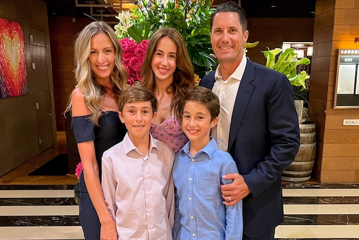 A family of five poses in front of a hillside.