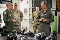 Two U.S. Air Force leaders stand talking with CBRN mask gear in front of them