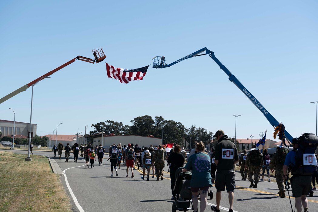 Airmen and their families walk under a large American flag.