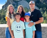 A family of five poses in front of a hillside.
