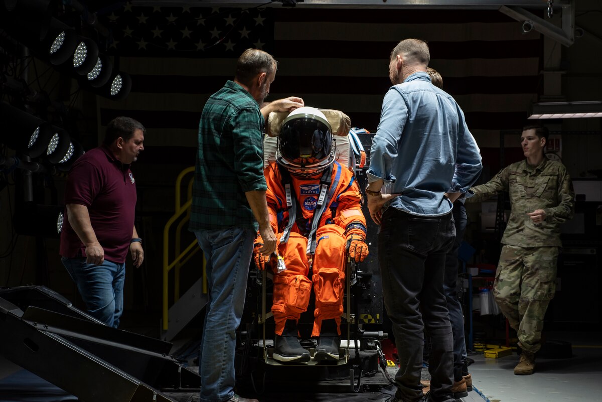 The Air Force Research Laboratory, or AFRL, and NASA staff adjust Campos, a fire and rescue training manikin, in the seat at the sled test facility at Wright-Patterson Air Force Base, Ohio, April 17, 2023. AFRL and NASA, along with other industry partners, such as Lockheed Martin, tested the most current iteration of an astronaut crew seat and flight suit that will be used on the Orion spacecraft during the next mission to the moon under the Artemis Program. The manikin used in the testing was Campos, named after the legendary Arturo Campos, an electrical engineer who was instrumental to saving the Apollo 13 crew. Campos is accurately weighed and has the appropriate density of a human for testing. (U.S. Air Force photo / Rick Eldridge)
