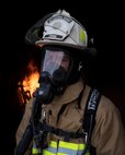 Firefighter stands in front of flames