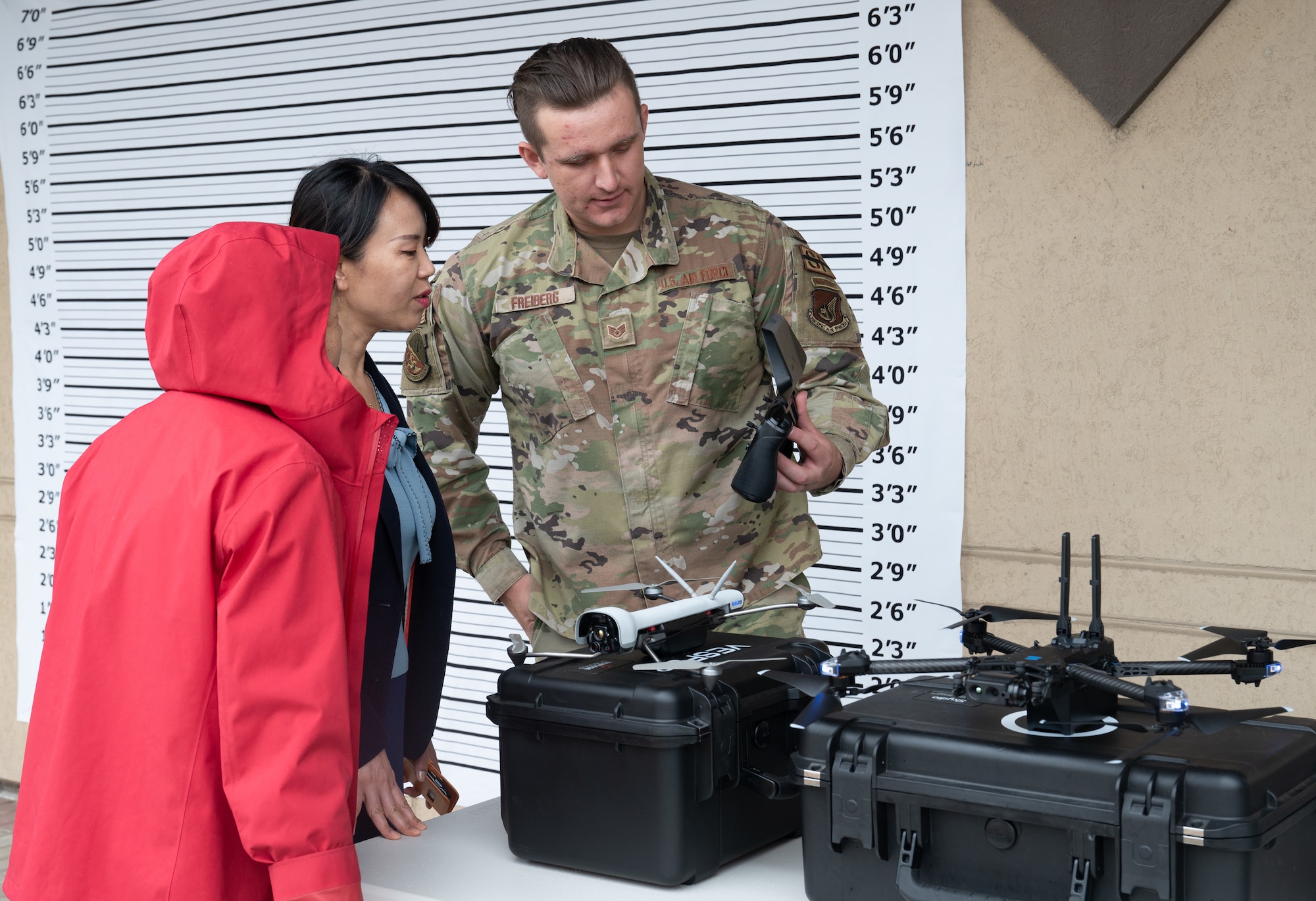 Two Korean nationals look at small-unmanned aircraft systems with Staff Sgt. Zackery Freiburg, 8th Security Forces Squadron NCO in charge of sUAS, during the 2023 National Police Week demonstration at Kunsan Air Base, Republic of Korea, May 22, 2023. During the demonstration, visitors could ask questions and get an inside look at some of the tactics, techniques and procedures used to defend the base. (U.S. Air Force photo by Staff Sgt. Sadie Colbert)