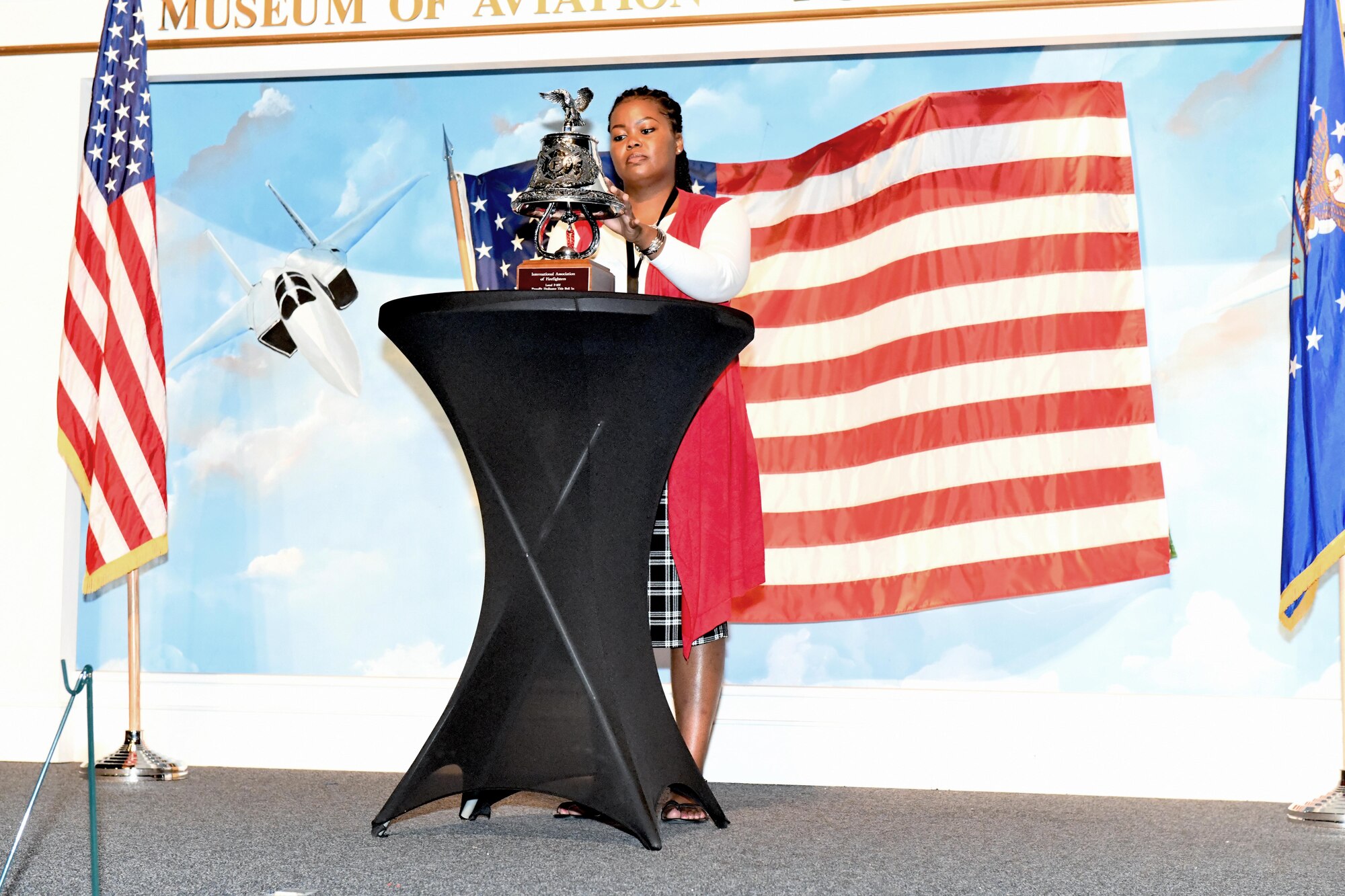 Woman standing on stage tolling a bell