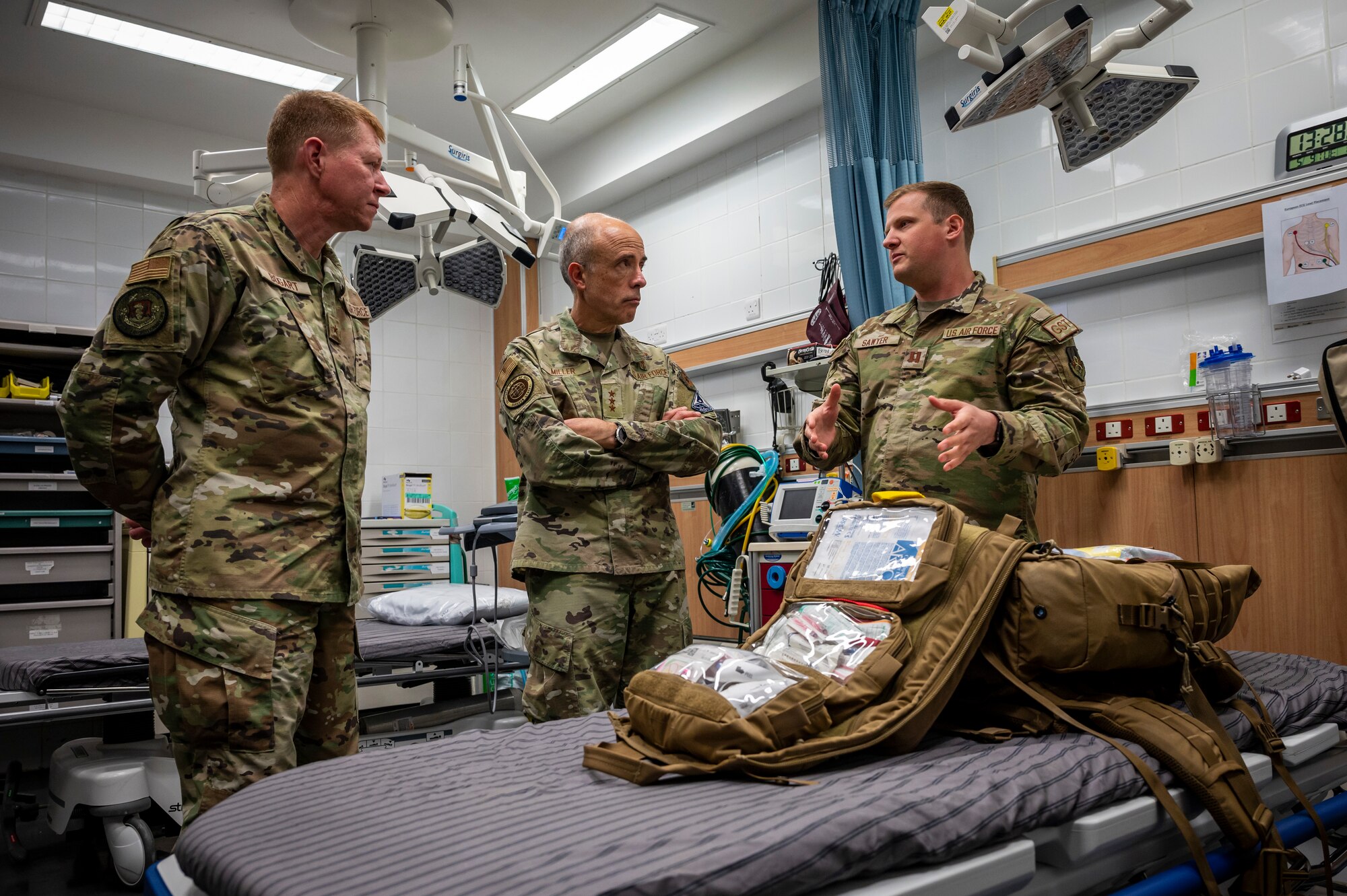 Group of military members stand around a bag filled with medical equipment.