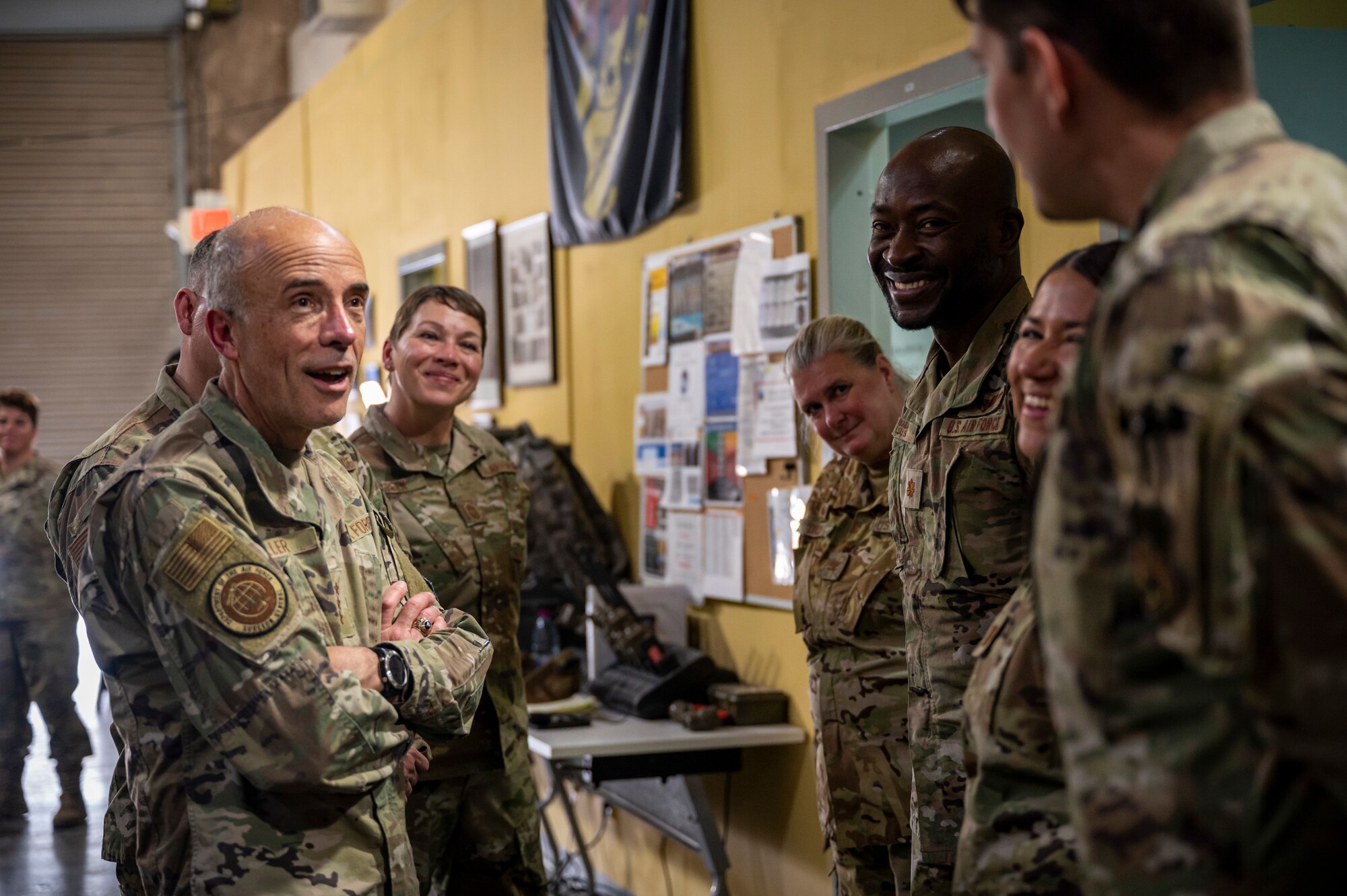 Military members stand in a group talking and laughing.