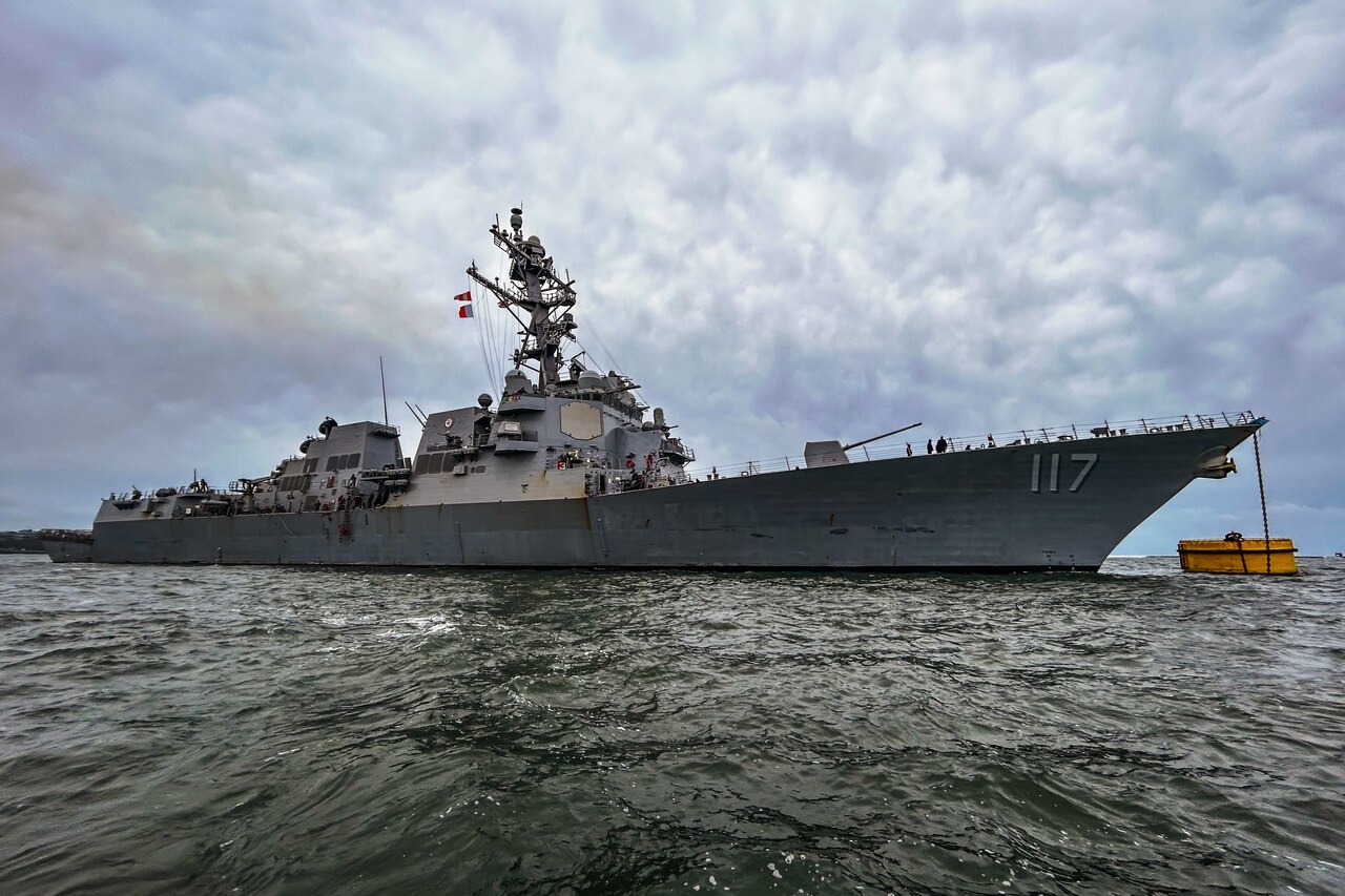 A large naval vessel sits under a cloudy sky.