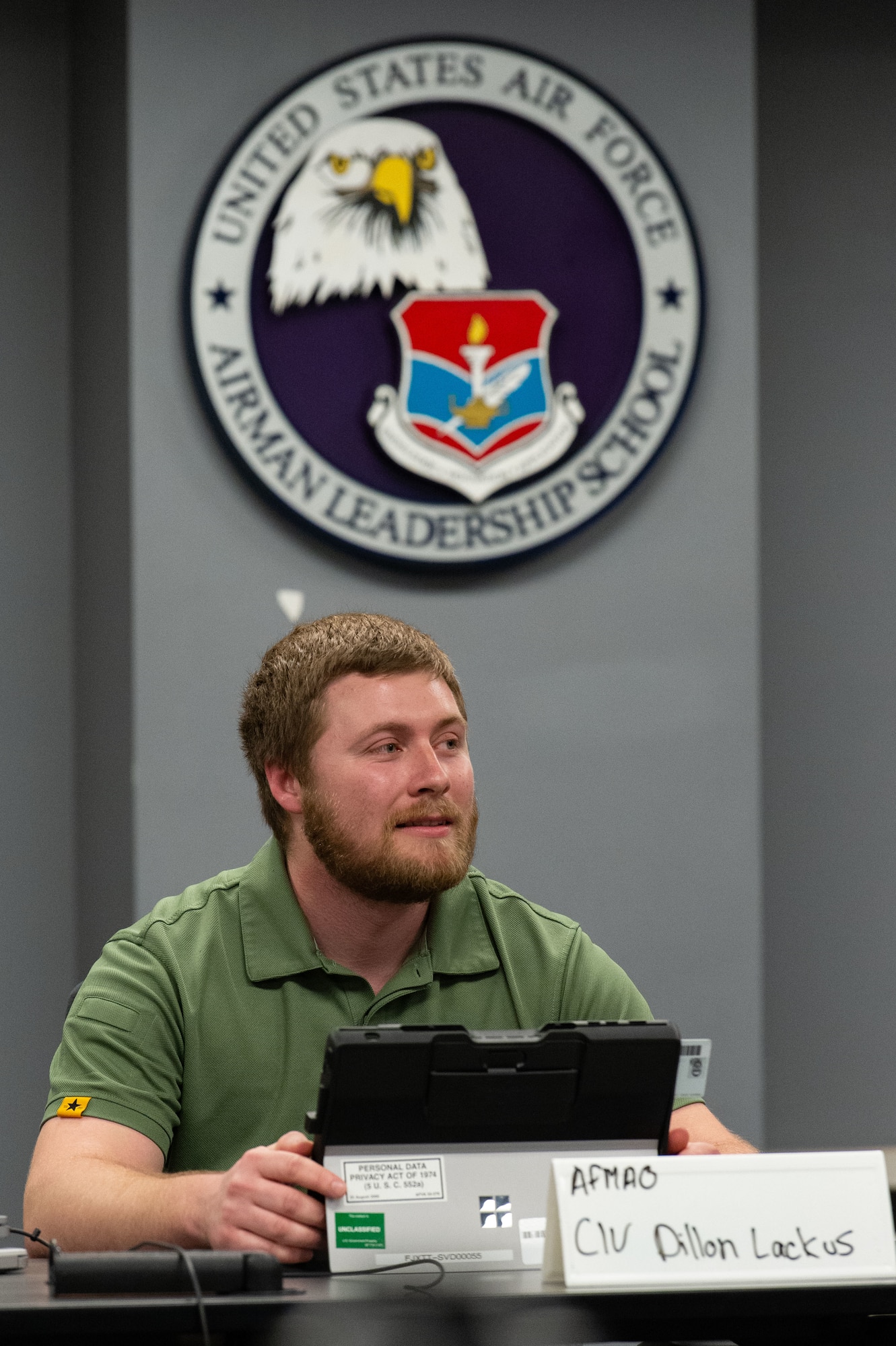 Dillon Lackus, Air Force Mortuary Affairs Operations mortuary clerk, listens to fellow Liberty Flight classmates at the Staff Sgt. Julio Alonso Airman Leadership School on Dover Air Force Base, Delaware, May 2, 2023. Lackus was the first civilian Airman to graduate from the five-week course that prepares military and civilian Airmen for leadership roles in the Air Force. (U.S. Air Force photo by Roland Balik)