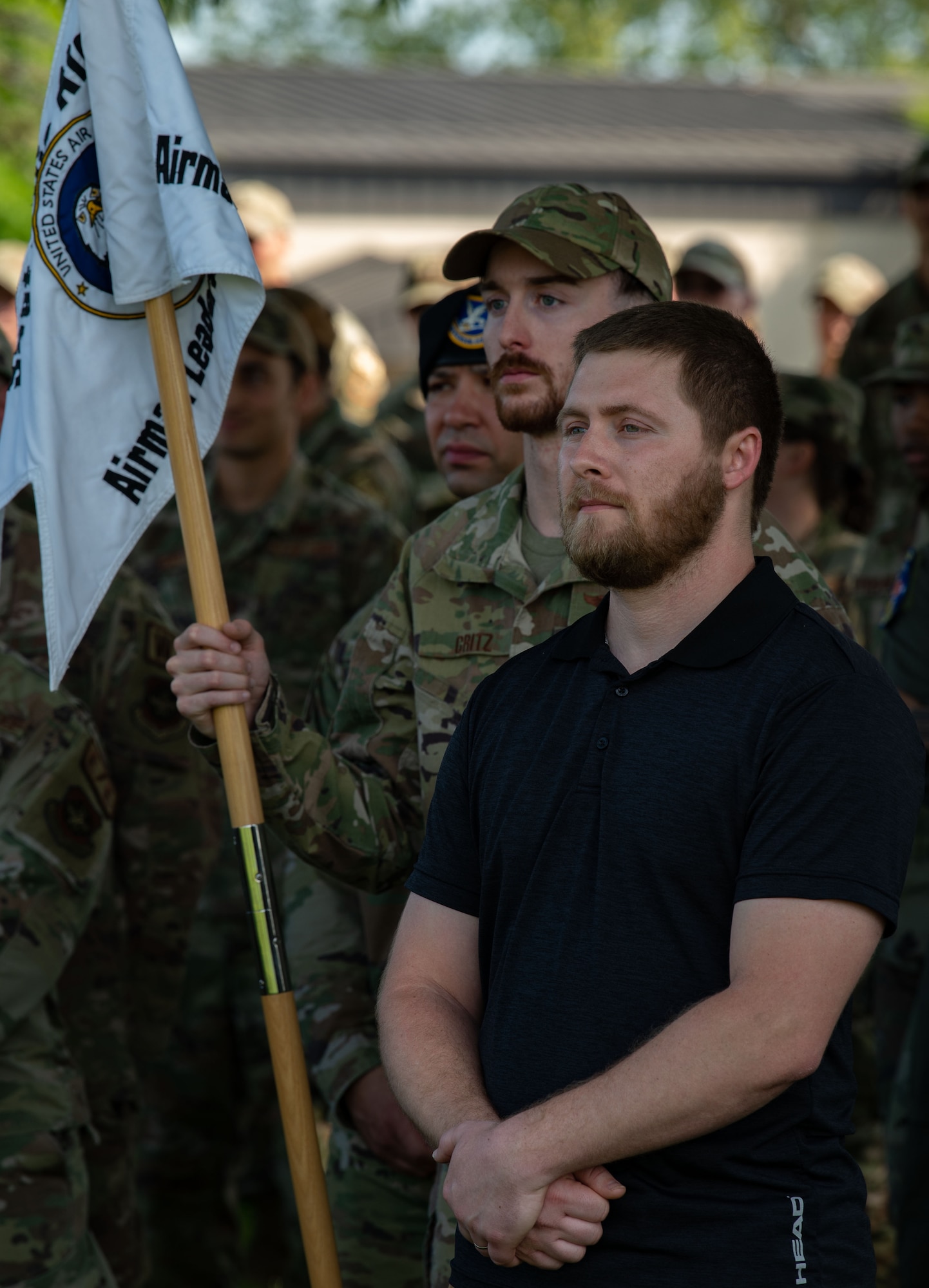 Dillon Lackus, right, Air Force Mortuary Affairs Operations mortuary clerk, listens to Col. Matt Husemann, 436th Airlift Wing commander, give closing remarks after Retreat at the base flag pole on Dover Air Force Base, Delaware, May 15, 2023. Lackus was the first civilian Airman to graduate from the five-week course that prepares military and civilian Airmen for leadership roles in the Air Force. The Staff Sgt. Julio Alonso Airman Leadership School, Class 23-E, and the 436th Mission Support Group hosted the Retreat in honor of Peace Officer Memorial Day. (U.S. Air Force photo by Roland Balik)