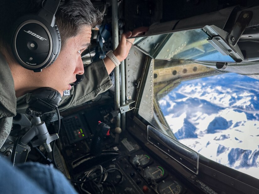 U.S. Air Force Airman 1st Class Joseph Saldana, a boom operator assigned to 50th Air Refueling Squadron, observes the Alaskan landscape during a refueling mission at Northern Edge 23-1 at Joint Base Elmendorf-Richardson, Alaska, May 18, 2023.
