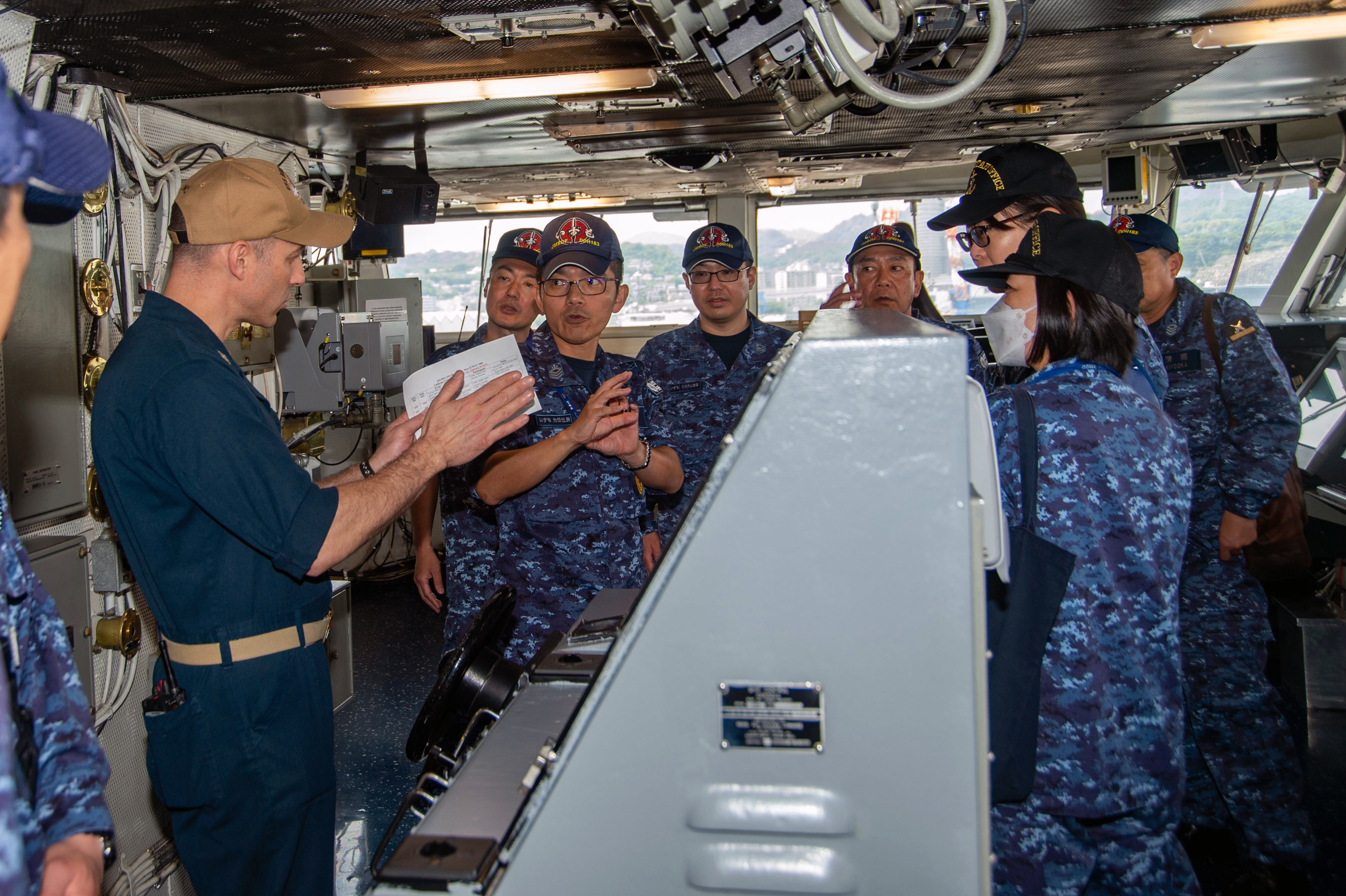 Command Master Chief Jeremy Douglas, command master chief of the U.S. Navy's only forward-deployed aircraft carrier, USS Ronald Reagan (CVN 76), gives members of the Japan Maritime Self-Defense Force helicopter destroyer JS Izumo (DDH 183) a tour of the bridge during a ship tour while in-port.